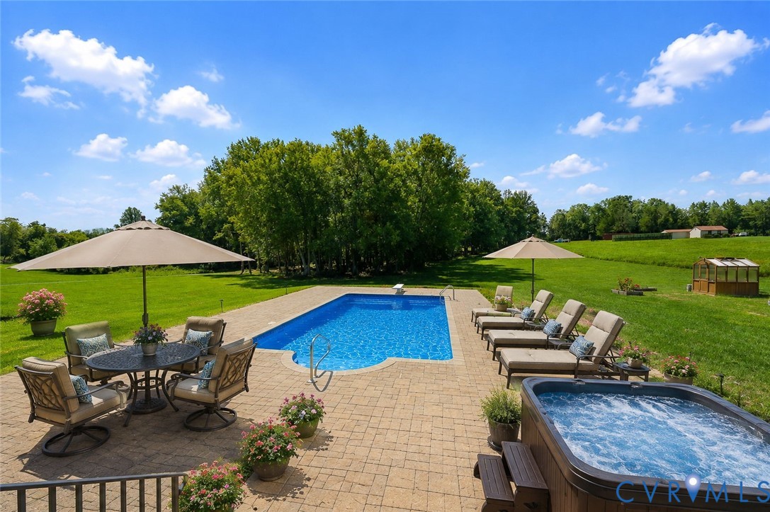 Expansive outdoor space featuring a rectangular inground pool, paver patio, and hot tub