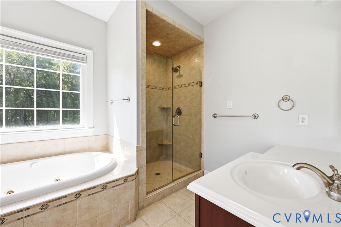 Soaking tub with tiled surround, adjacent to a glass-enclosed shower with tiled walls and built-in bench