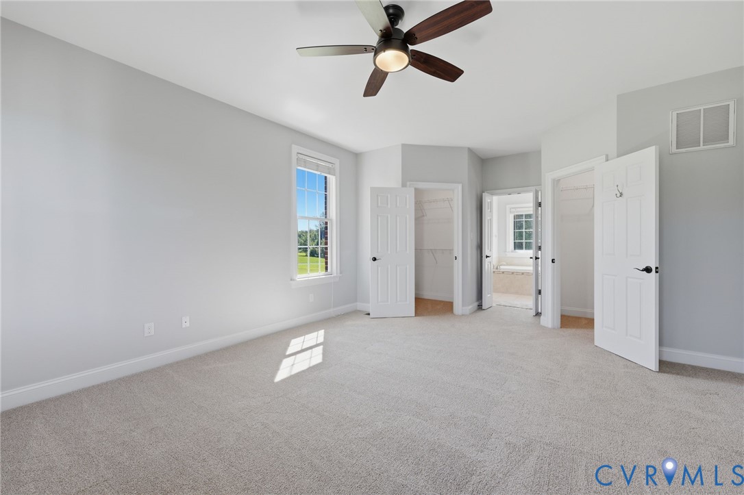 Carpeted room featuring a ceiling fan with integrated lighting, a single window, and multiple doorways