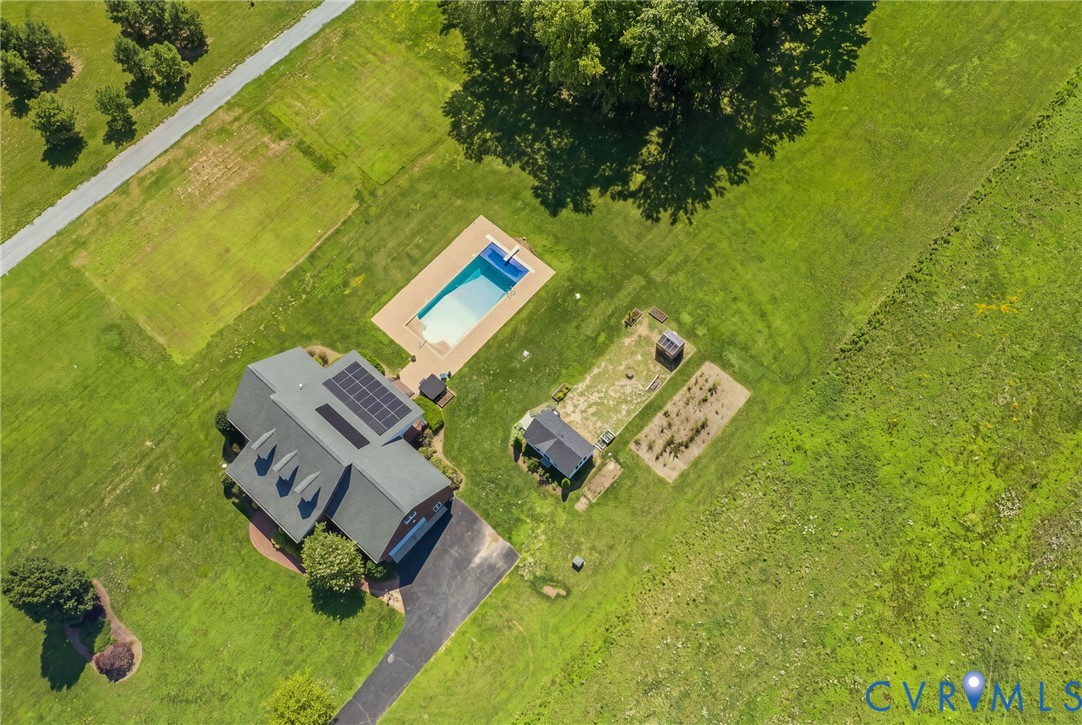 Aerial perspective of a property featuring a rectangular swimming pool with a surrounding paved deck