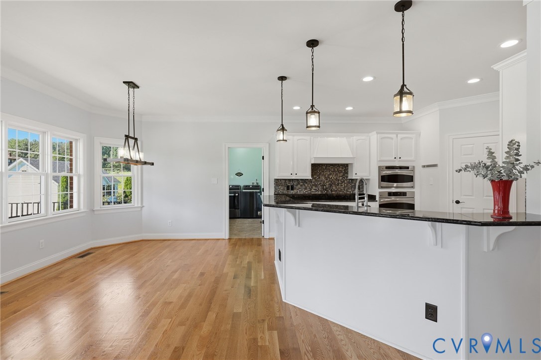 Kitchen featuring a multi-level breakfast bar with dark countertop, white cabinetry, and stainless steel built-in appliances