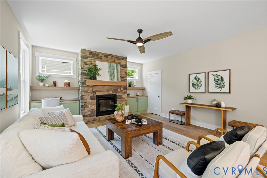Living area featuring a stone-clad fireplace with wood mantle, built-in cabinetry, and wood-finish flooring