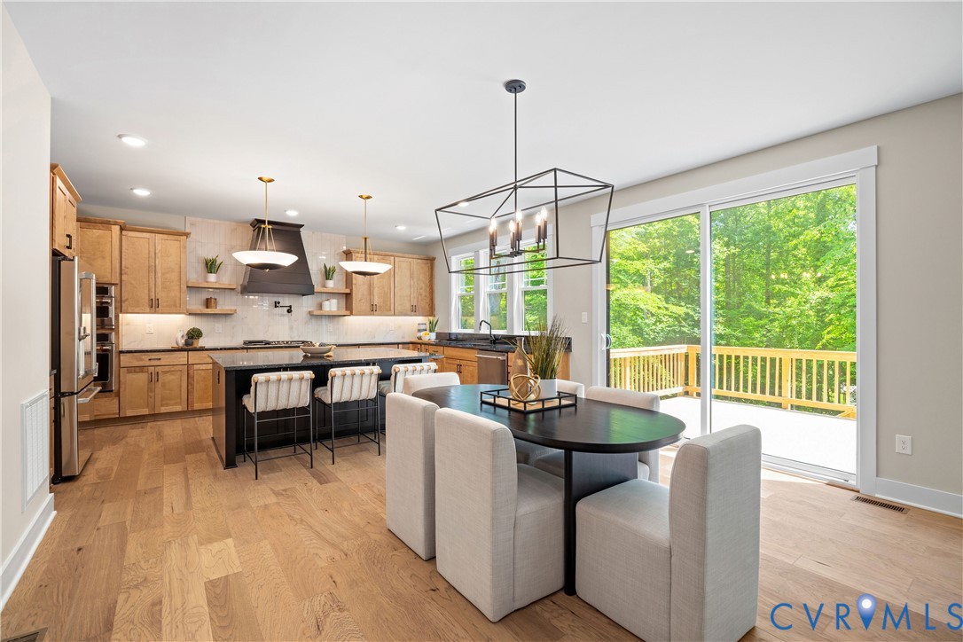 Open-concept kitchen and dining area featuring wood-finish flooring, recessed lighting, and a modern geometric chandelier