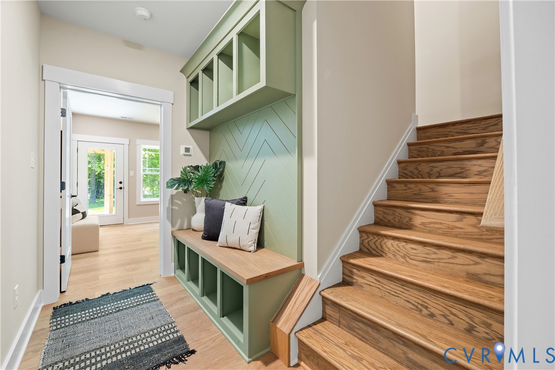 Hardwood staircase featuring light wood-finish flooring and a built-in bench with storage cubbies