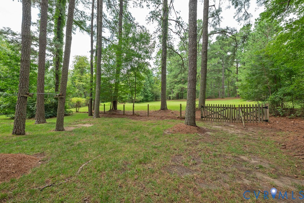 View from center of fenced yard towards cleared land and woods further back