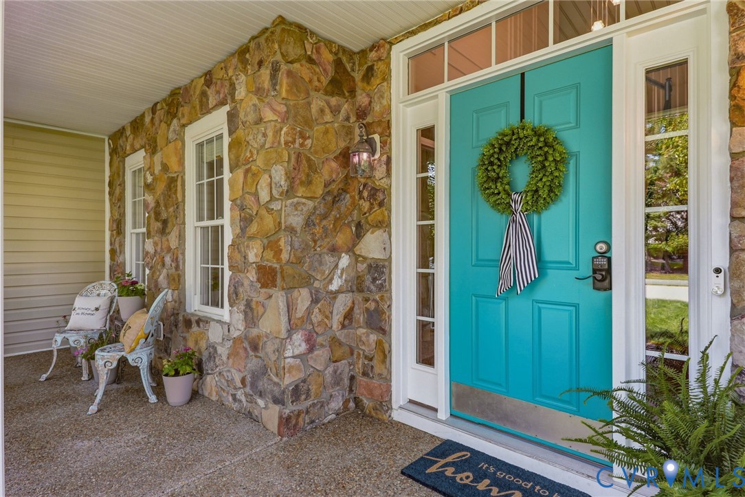 Stone facade exterior with a vibrant turquoise front door, flanking sidelight windows, and transom window