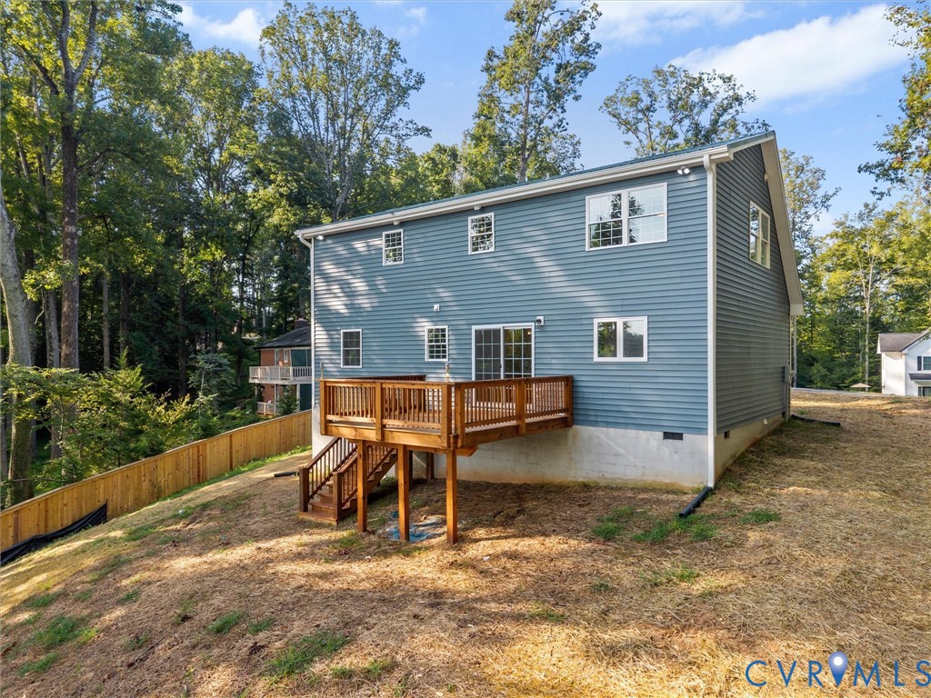 Multi-story exterior with blue siding, a multi-level deck, and a wooden privacy fence
