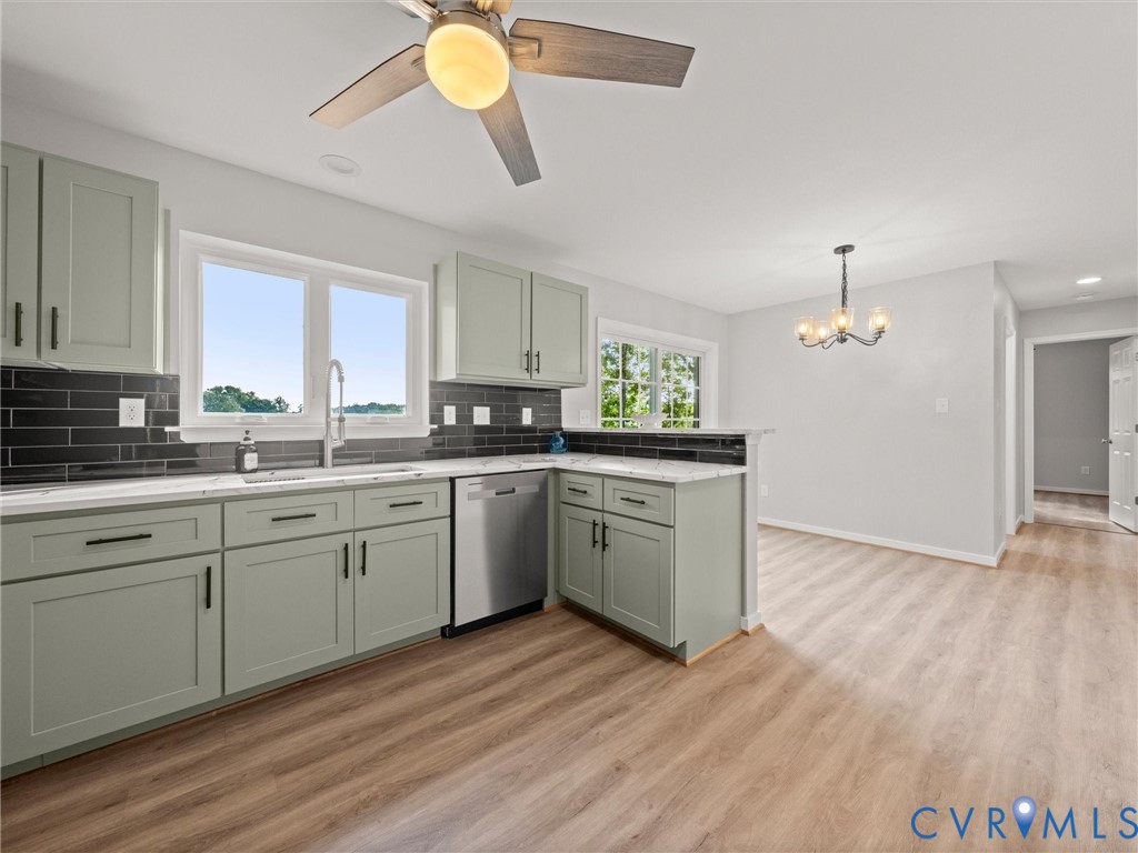 Kitchen featuring sage cabinetry, white countertops, black subway tile backsplash, and stainless steel appliances
