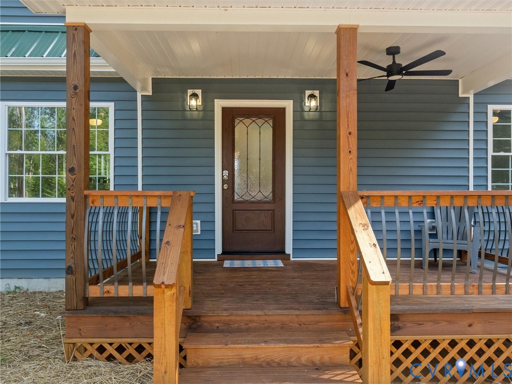 Front porch featuring wood steps, wood pillars, wood railing with metal balusters, and a dark wood entry door with decorative glass