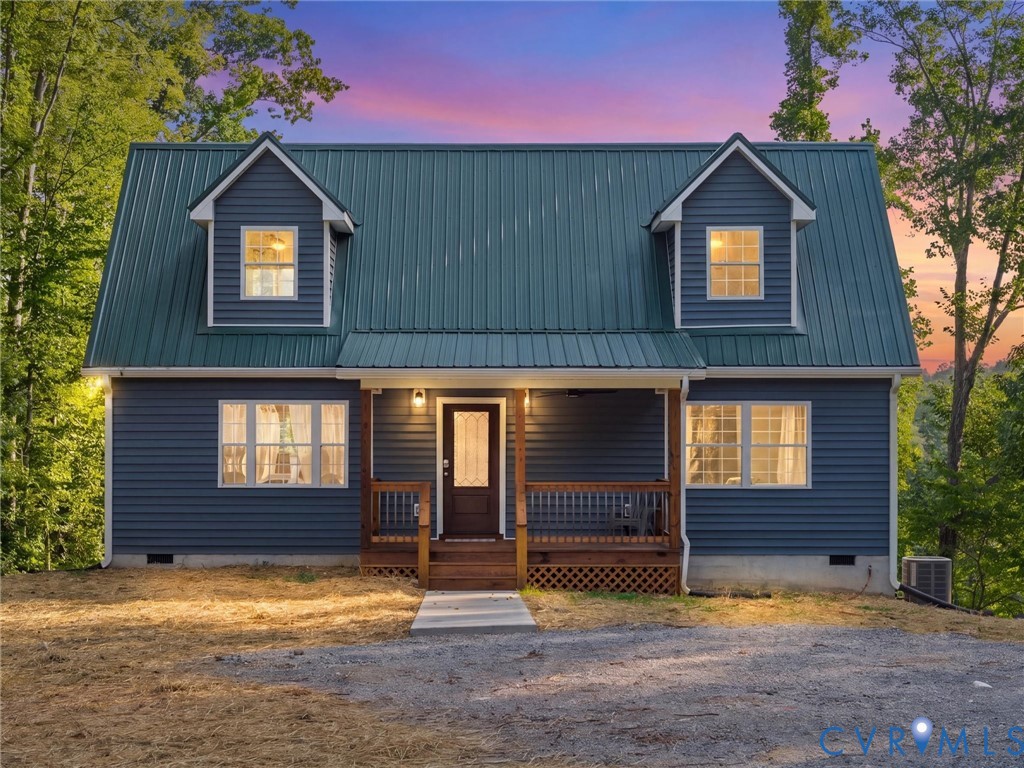 Two-story residence featuring a dark blue siding exterior, a green metal roof, and two dormer windows Two-story residence featuring a dark blue siding exterior, a green metal roof, and two dormer windows