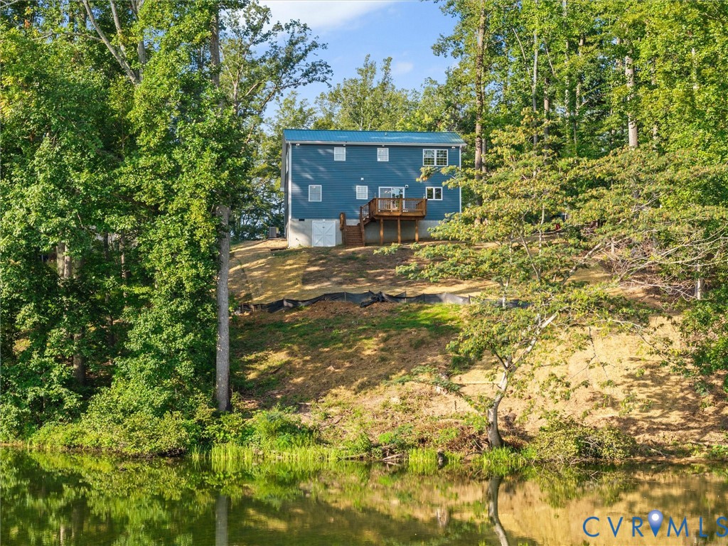 Blue siding exterior with a metal roof, featuring a wood-finish deck and surrounding mature trees
