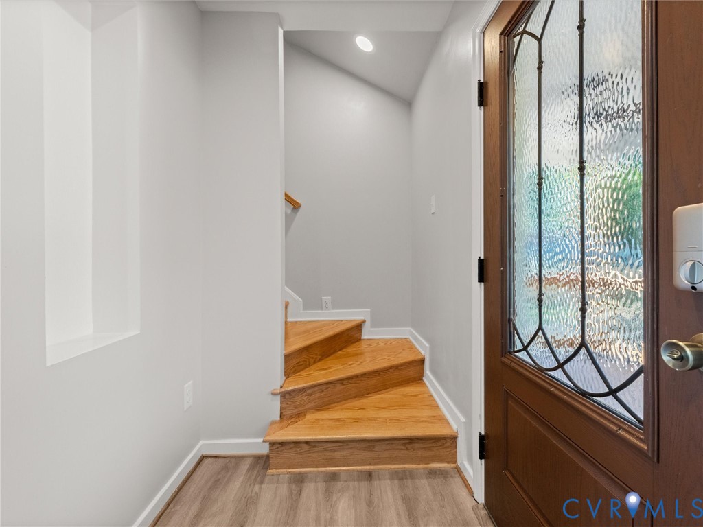 Wood-finish flooring, hardwood staircase, recessed lighting, and a leaded glass entry door