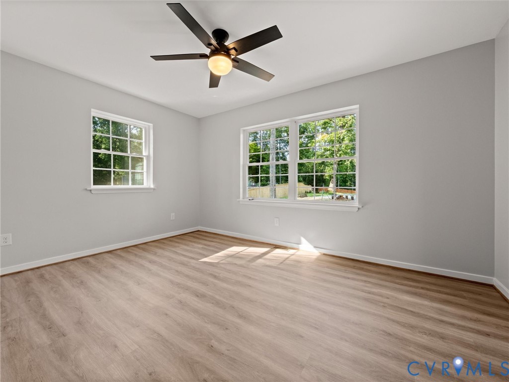 Light wood-finish flooring, white trim, and a ceiling fan with integrated lighting