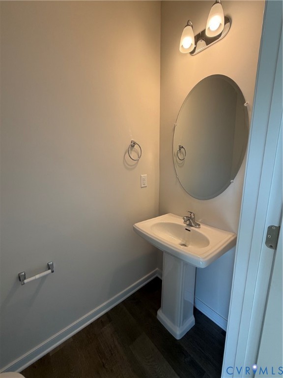 Pedestal sink with chrome faucet, oval mirror, and contemporary two-light vanity fixture