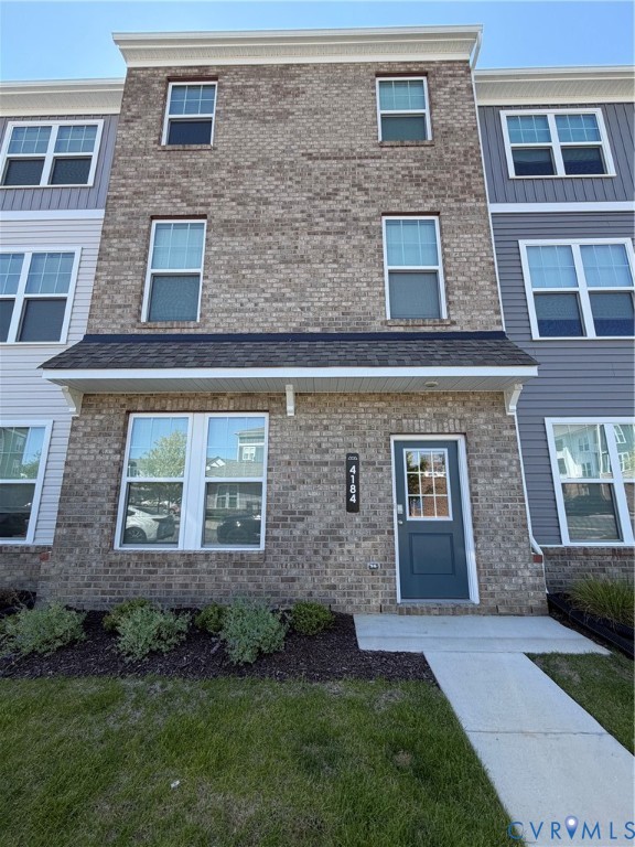 Multi-story townhouse featuring a brick facade with light gray siding accents