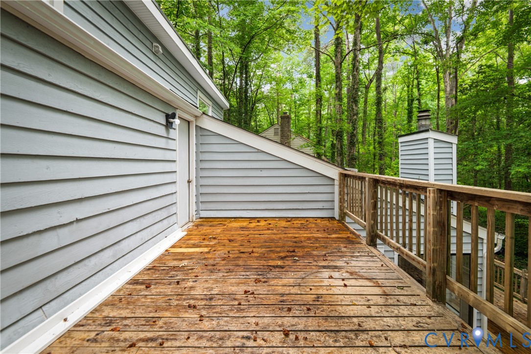 Spacious composite deck featuring warm wood-finish decking, white horizontal vinyl siding, and wooden railings with turned balusters
