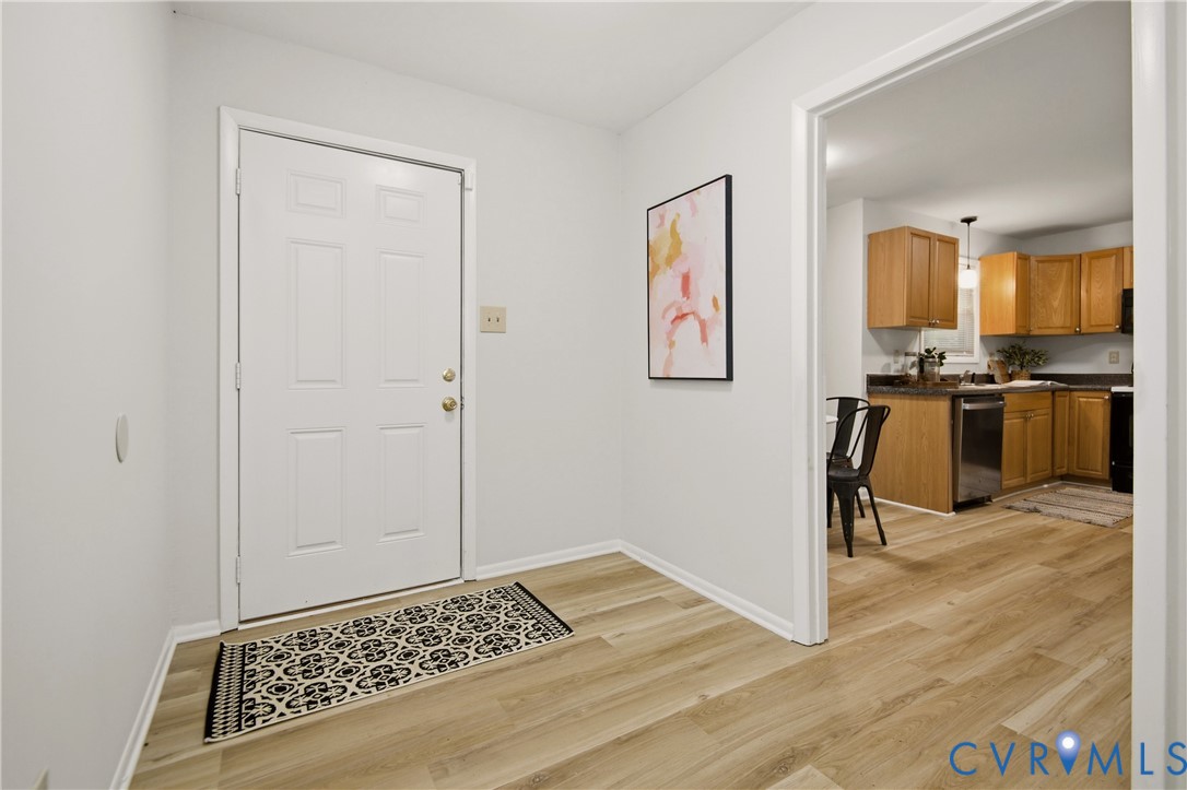 Entryway with light wood-finish flooring and a white paneled door Entryway with light wood-finish flooring and a white paneled door