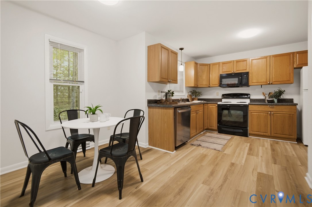 Eat-in kitchen featuring wood-finish flooring, ample cabinetry, black appliance suite, and a stainless steel dishwasher