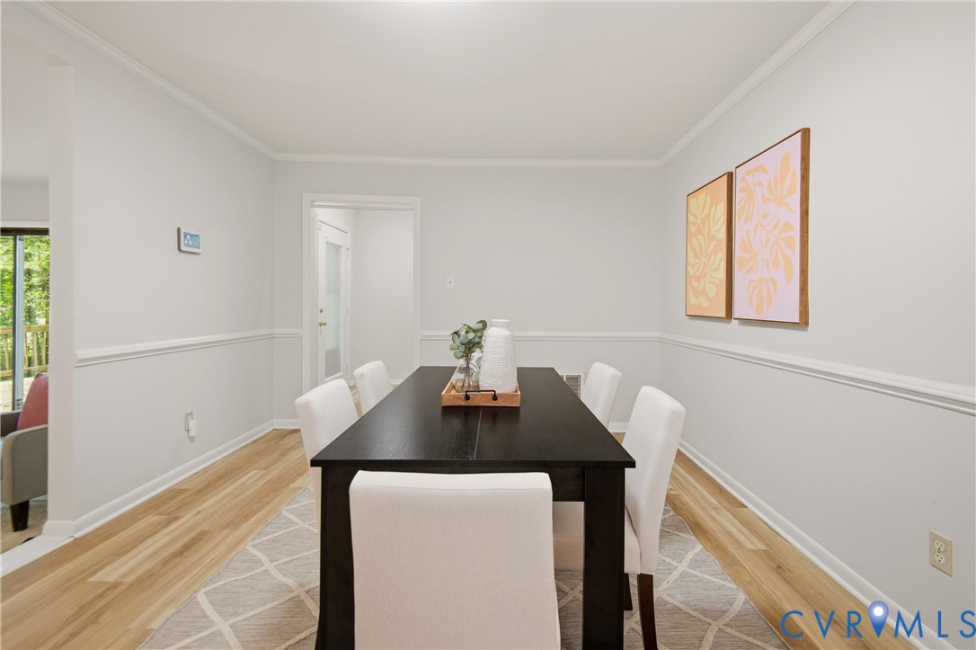 Dining area featuring light-tone wood-finish flooring, crown molding, and chair rail detailing
