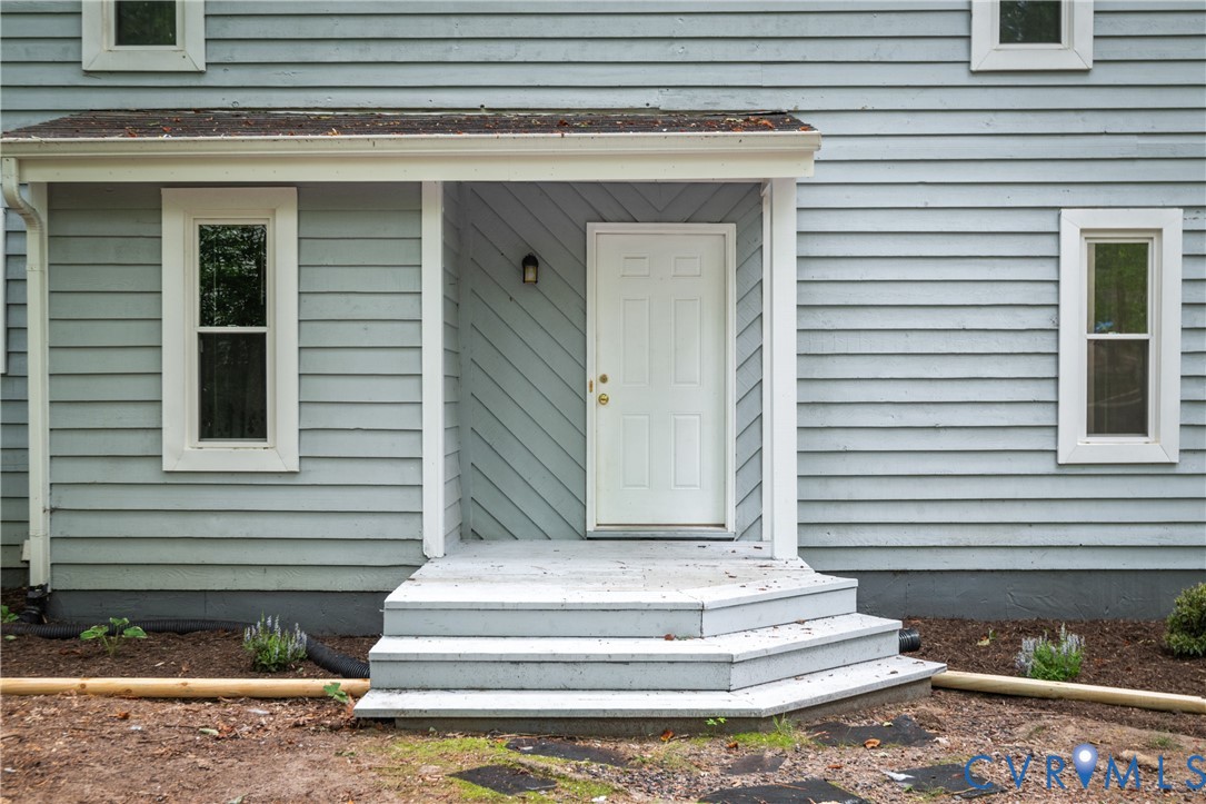 Front porch entry with a paneled door, exterior lighting, and multi-level steps