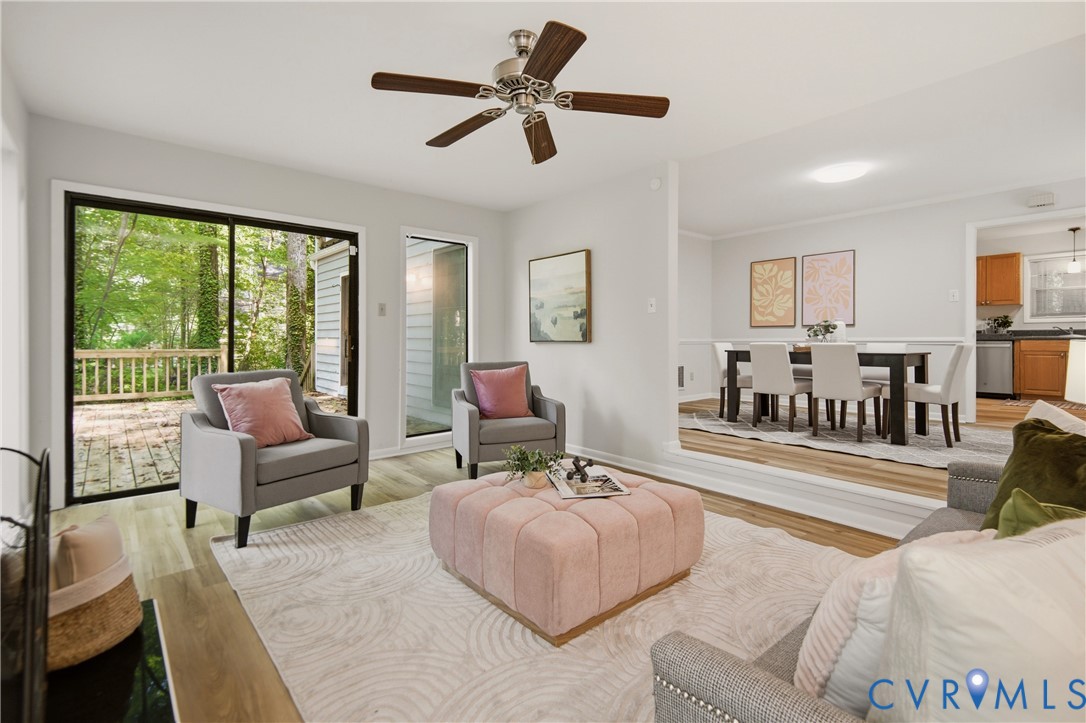 Spacious living area featuring wood-finish flooring, a ceiling fan, and a sliding glass door opening to an outdoor deck Spacious living area featuring wood-finish flooring, a ceiling fan, and a sliding glass door opening to an outdoor deck