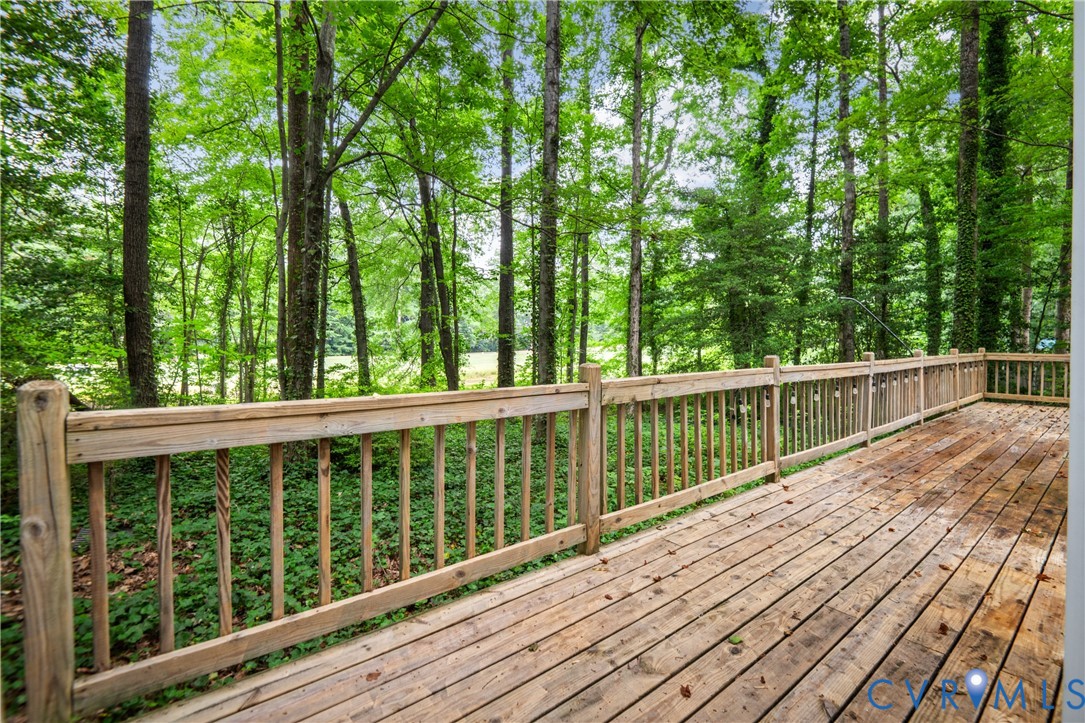 Expansive composite deck featuring pressure-treated wood decking with integrated wooden railings and balusters, overlooking a mature forest canopy