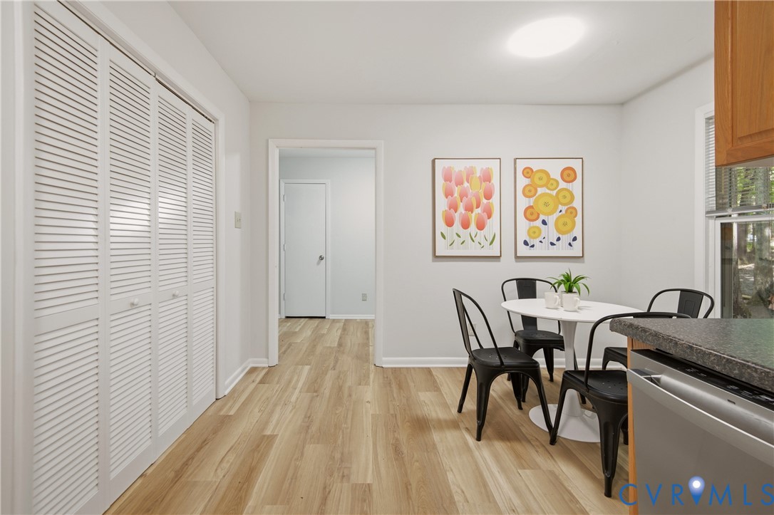 Dining area featuring wood-finish flooring, a contemporary overhead light fixture, and a window with blinds