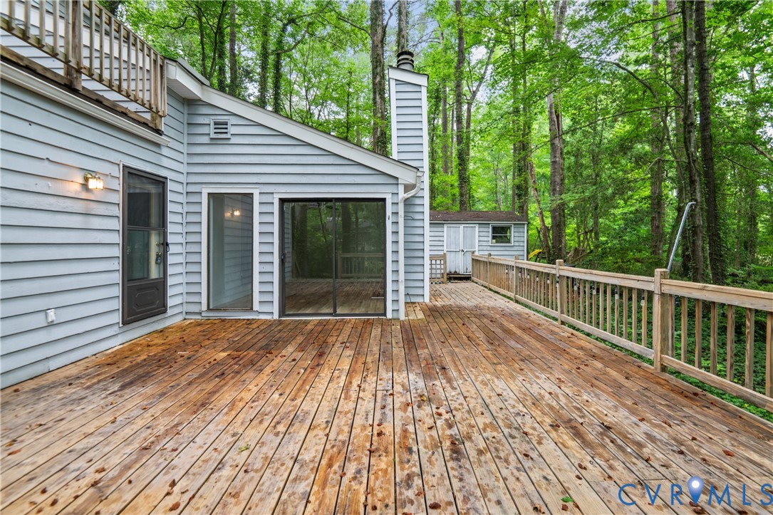 Expansive wooden deck with a built-in railing, offering access to an enclosed porch and a separate exterior door