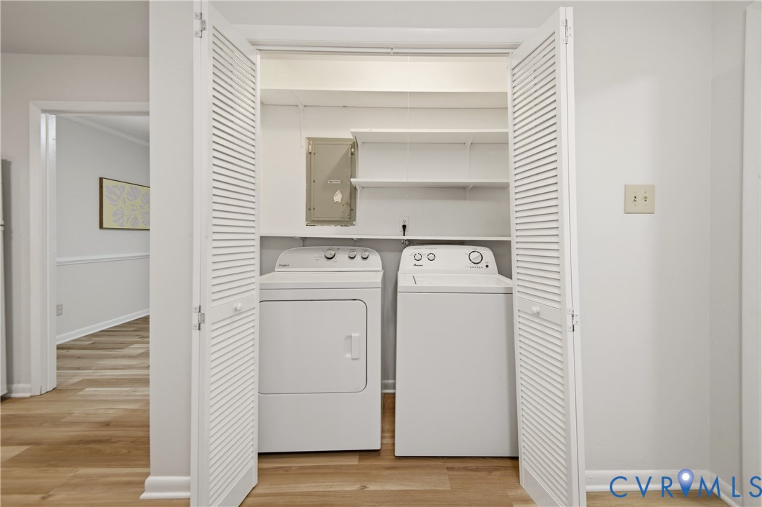 Dedicated laundry closet with bi-fold louvered doors, integrated shelving, and wood-finish flooring