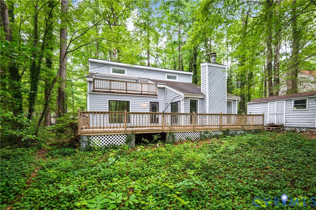 Contemporary home featuring a multi-level deck with wood railings and horizontal siding, set among mature landscaping