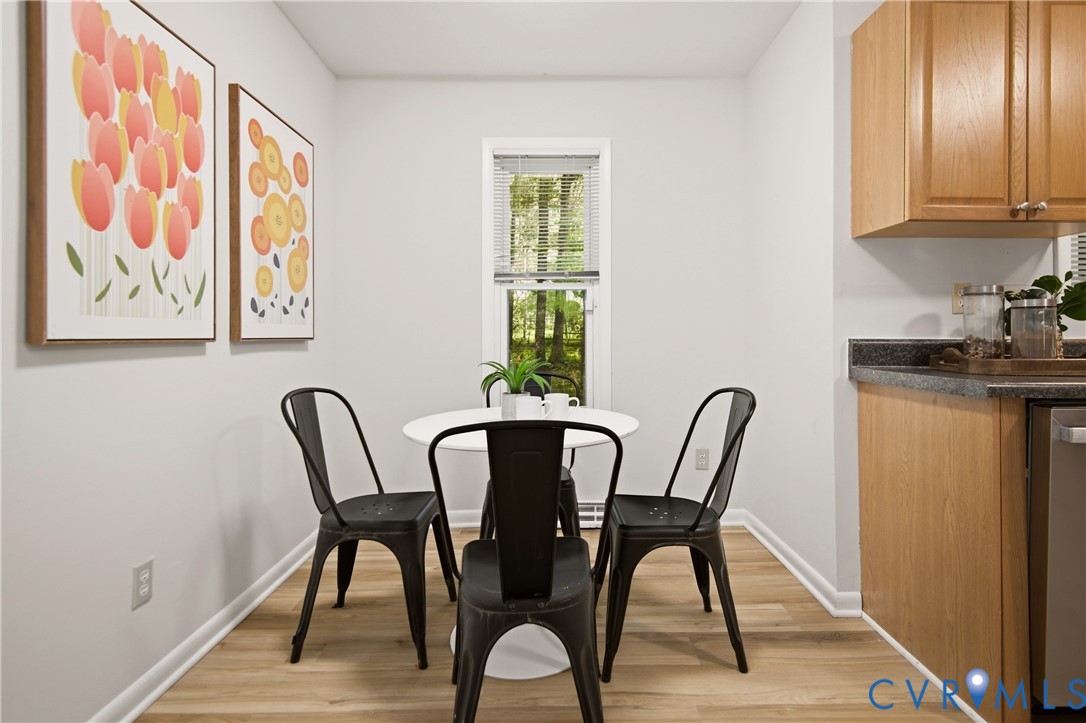 Kitchen dining area featuring wood-finish flooring and a single window with blinds