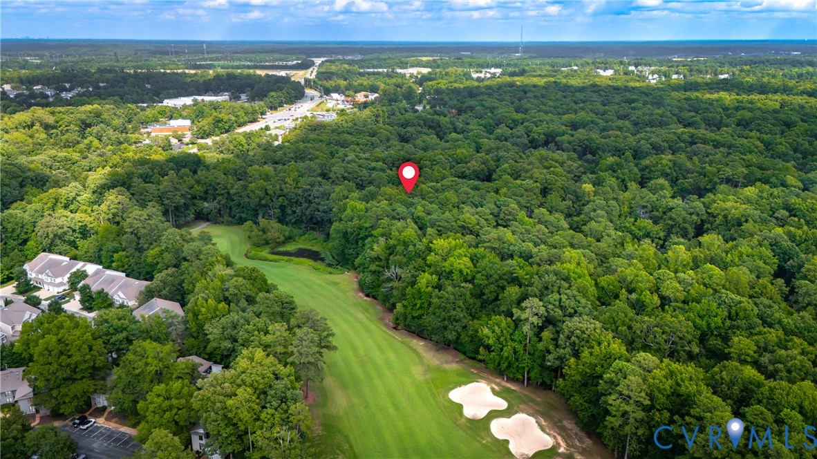 Aerial view showcasing expansive grounds with manicured fairway-style lawn, mature tree-lined perimeter, and integrated golf course amenities including sand bunkers