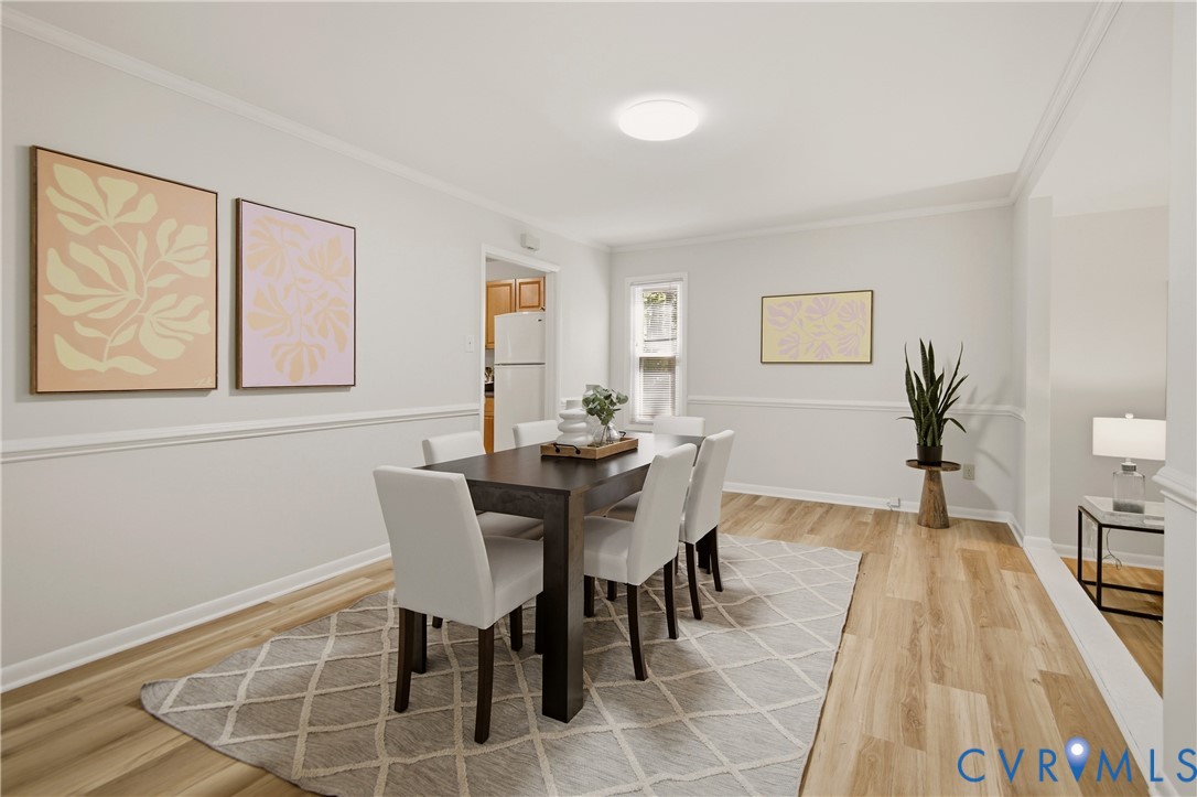 Elegant dining room featuring a dark wood table with upholstered chairs, crown molding detail, and wainscoting throughout