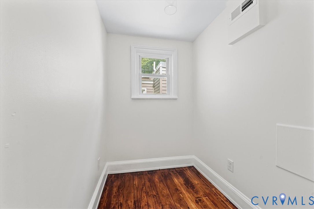 Warm wood-finish flooring, white painted walls, and a recessed ceiling light