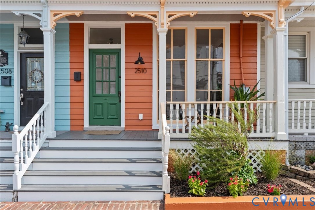Vibrant exterior with orange and blue siding, white railings, and a green entry door