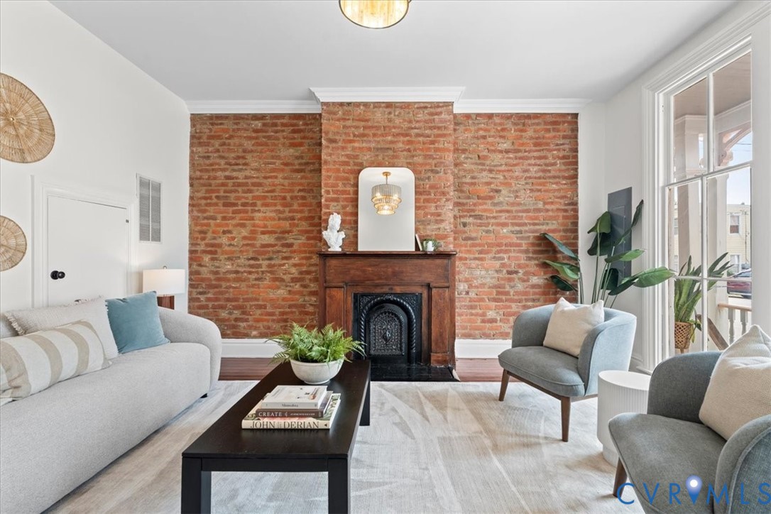 Exposed brick accent wall, wood-finish flooring, and crown molding