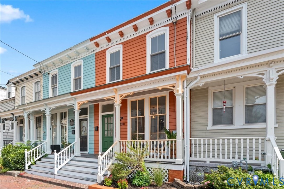 Vibrant multi-story facade with ornate white trim, an inviting front porch, and a classic green entry door
