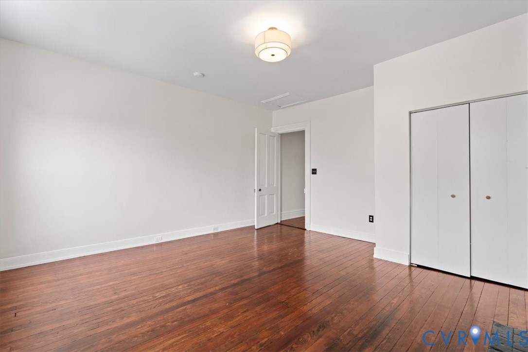 Hardwood flooring, white walls, flush mount ceiling light, white bi-fold closet doors, and white interior door