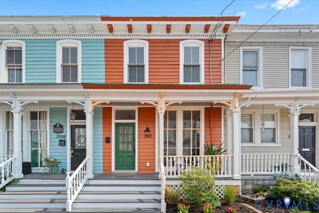 Ornate porch with white balustrade, decorative corbels, and a green front door