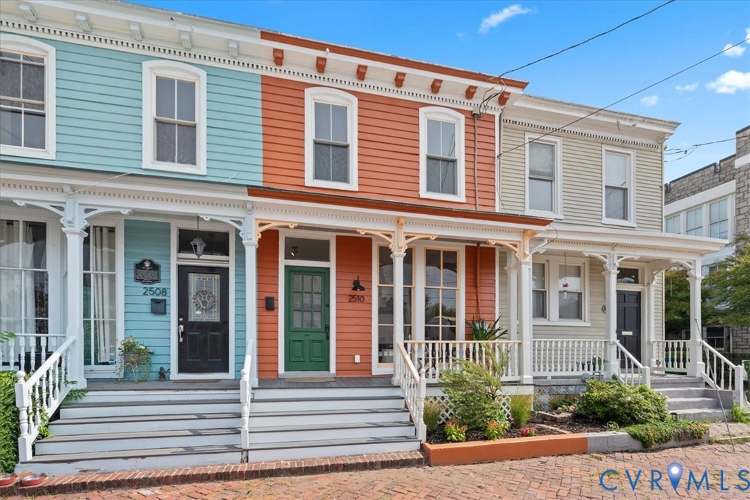Vibrant exterior showcasing varied siding colors, white trim, decorative porch railings, and individual front doors with transom windows
