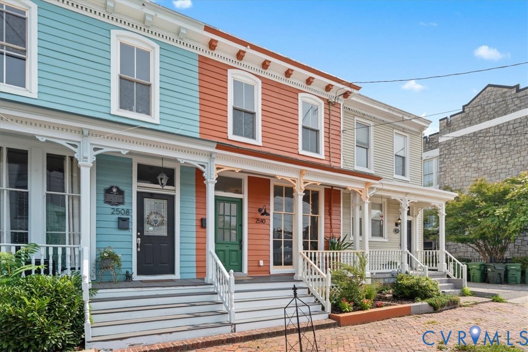 Architectural features include decorative porch columns, white window trim, and horizontal siding