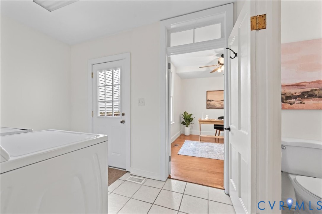 White tiled flooring, white painted walls, and a white paneled door with window inserts