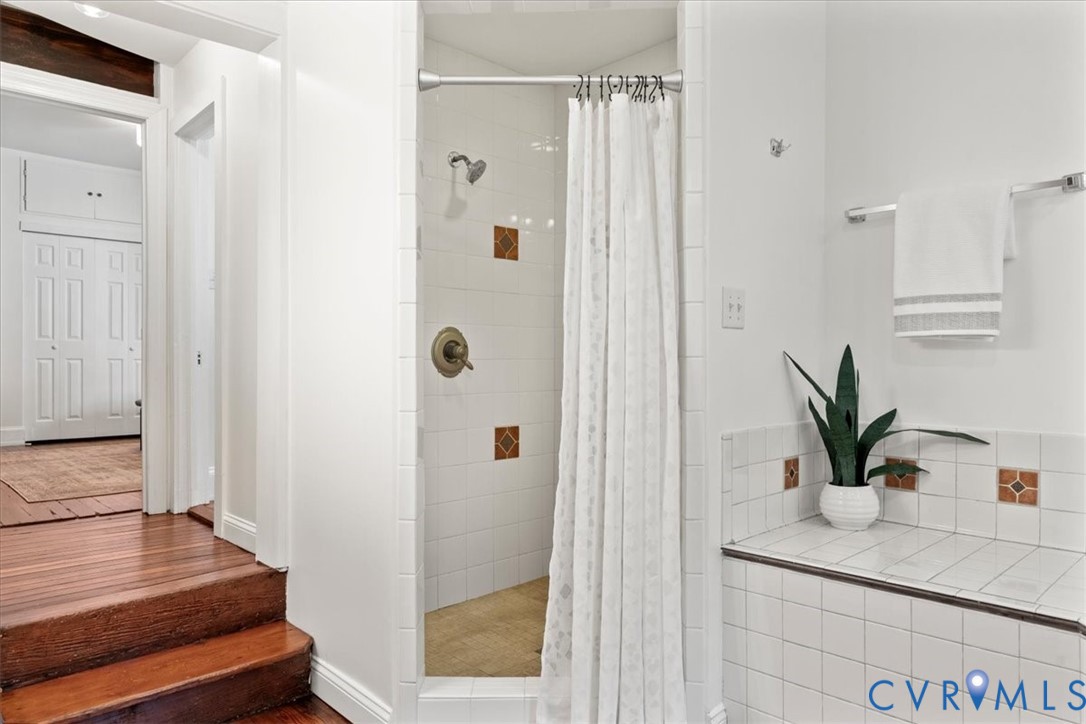 Tiled shower enclosure with bronze-finish fixtures, white wall tile, and accent tiles