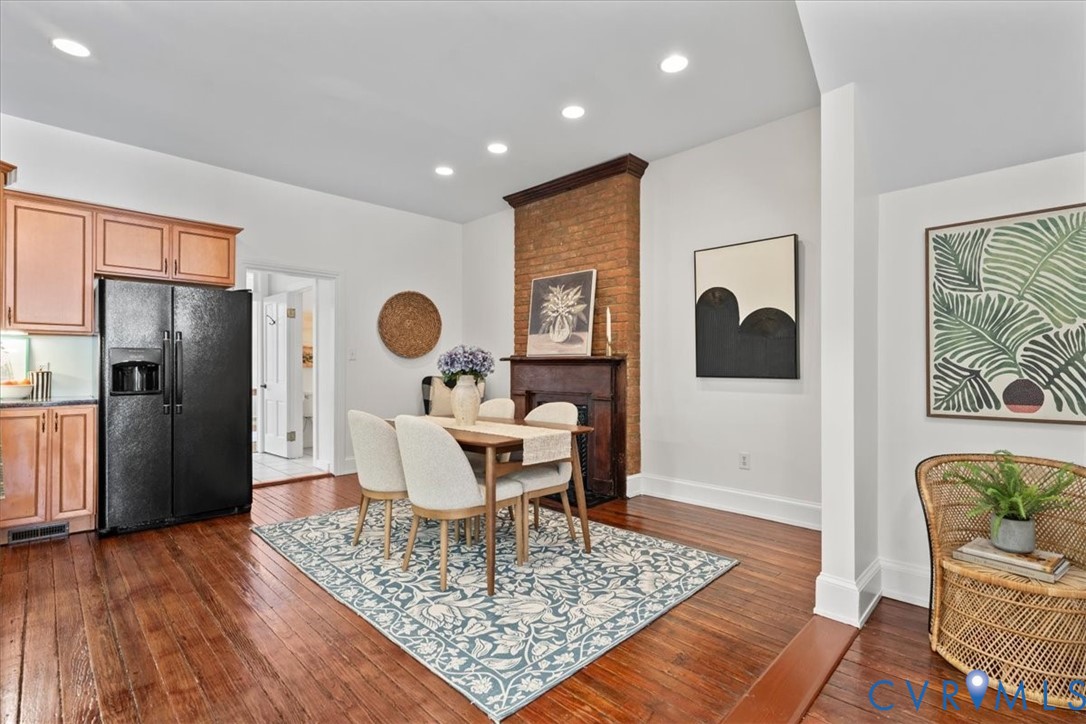 Hardwood flooring throughout, recessed lighting, exposed brick accent wall, and a built-in kitchen refrigerator