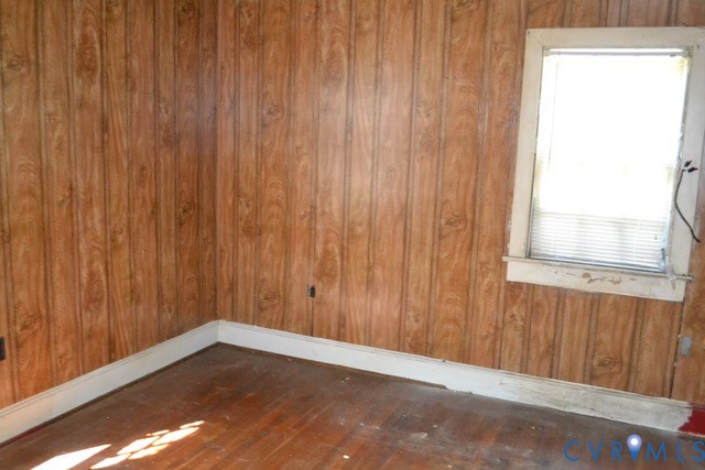 Wood-look paneling walls, wood-finish flooring, and a single pane window with blinds