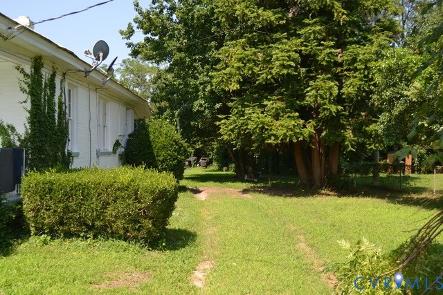 White exterior siding with vine accents, manicured hedges, and mature trees