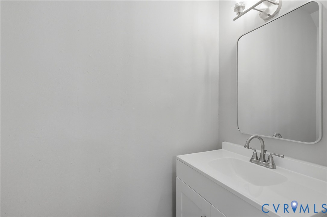White vanity with an integrated sink, brushed nickel faucet, and a wall-mounted rectangular mirror