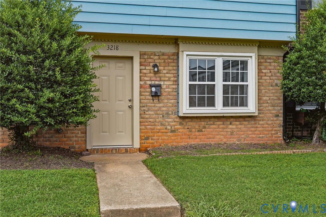 Brick facade with blue siding accent and a paneled entry door