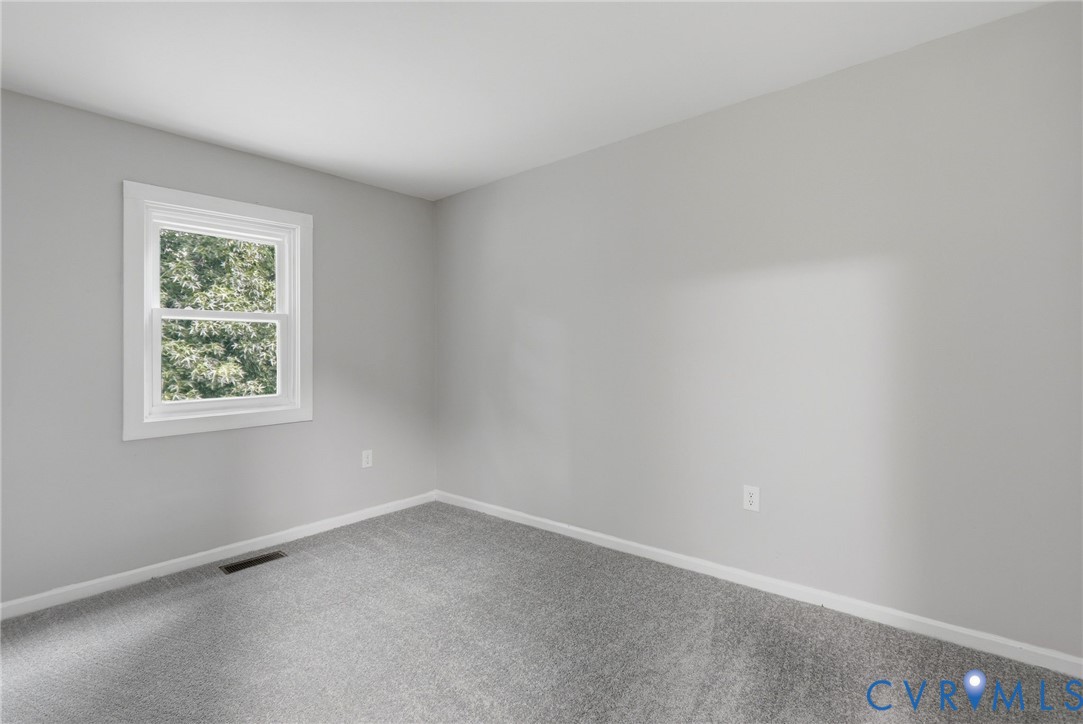 Room featuring light grey wall paint, grey patterned carpeting, and white baseboards
