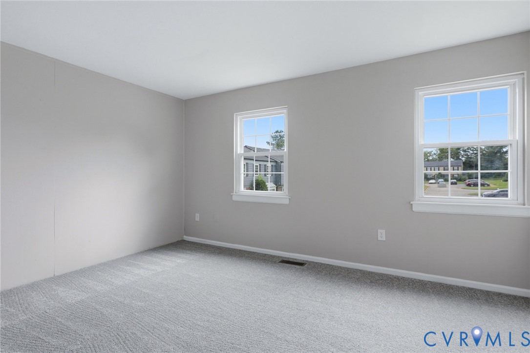 Bright interior space featuring light gray walls, white trim, and a gray patterned carpet
